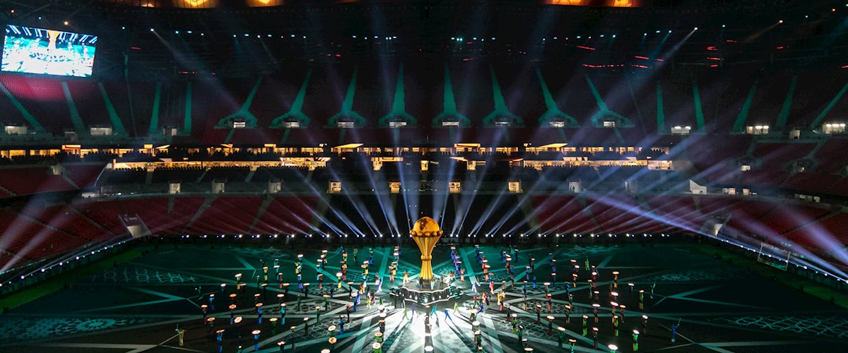An overview image taking at the TotalEnergies CAF Africa Cup of Nations 2025 Opening Ceremony at Prince Moulay Abdellah Stadium in Rabat, Morocco. On the field multiple dancers are holding Hex Panels a technical solution designed and engineered by PRG Projects. The hex shaped portable LED screens are displaying different colors and shapes.