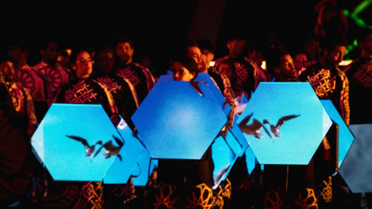 A close up of 3 dancers holding Hex Panels gen 2 at the TotalEnergies CAF Africa Cup of Nations 2025 Opening Ceremony. The hex panels were a technical solution created by PRG Projects. The Portable Hexagonally shaped LED screens are displaying the sky and flying seagulls.